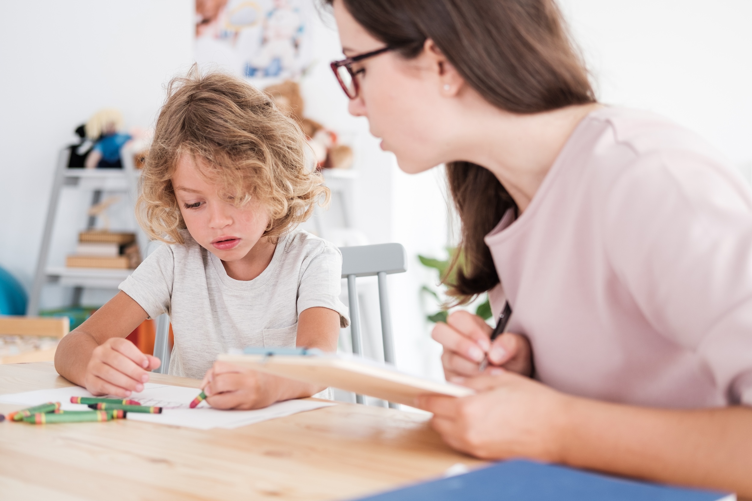 a,psychotherapist,watching,a,child,draw,pictures,with,crayons,during